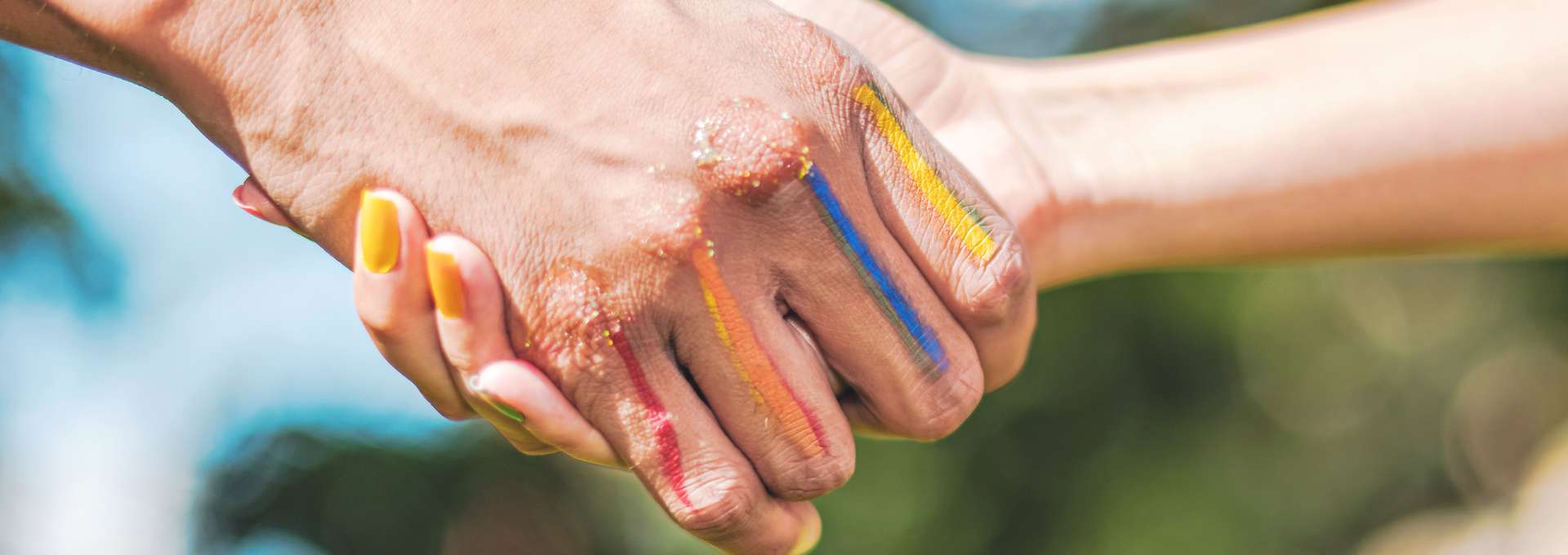 Två händer med regnbågsfärger på fingrarna som skakar hand